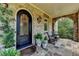 Cozy front porch with an arched brick design, decorative iron door and comfortable seating at 4745 Cuyahoga Cv, Suwanee, GA 30024