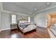 Comfortable main bedroom with wooden floors, tray ceiling, plantation shutters, and an ensuite bathroom at 4745 Cuyahoga Cv, Suwanee, GA 30024
