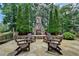 Inviting outdoor stone fireplace, Adirondack chairs and lush landscaping create a serene backyard gathering space at 4745 Cuyahoga Cv, Suwanee, GA 30024