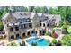 An impressive rear exterior featuring multiple covered patios, a pool, and beautifully landscaped gardens at 4745 Cuyahoga Cv, Suwanee, GA 30024