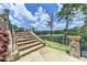 Elegant stone staircase with metal railings, lush landscaping, and a glimpse of the lake and golf course at 4745 Cuyahoga Cv, Suwanee, GA 30024