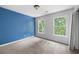 This bedroom features neutral carpet, bright blue accent wall, and large windows at 2108 Yorkshire Ct, Woodstock, GA 30189