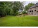 Large backyard features a lush green lawn surrounded by mature trees and a fire pit area at 610 Woodstream Ct, Roswell, GA 30075