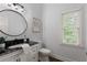 Half bathroom featuring white cabinets, black granite countertop, round mirror, and a window at 610 Woodstream Ct, Roswell, GA 30075