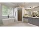 Bright bathroom with modern tub, walk-in shower, gray vanity, and a large window at 610 Woodstream Ct, Roswell, GA 30075