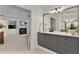Bathroom with dual sinks, gray cabinets, and an open doorway to the main bedroom at 610 Woodstream Ct, Roswell, GA 30075