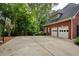 Spacious driveway with basketball hoop and two-car garage, framed by lush trees and classic brick exterior at 610 Woodstream Ct, Roswell, GA 30075