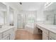 Bathroom offering separate vanities, a glass-enclosed shower, and a soaking tub beneath a window with decorative shutters at 645 Ruxbury Ct, Suwanee, GA 30024