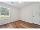 Clean bedroom featuring wood-look floors, a window with blinds, white trim, and a white door at 645 Ruxbury Ct, Suwanee, GA 30024