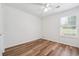 An empty bedroom with hardwood-style floors, white walls, a ceiling fan, and a window offering natural light at 645 Ruxbury Ct, Suwanee, GA 30024
