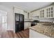 This kitchen showcases granite countertops, stainless appliances, wood floors and a black refrigerator at 645 Ruxbury Ct, Suwanee, GA 30024
