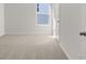 Bright, empty bedroom with a view of the neighborhood, neutral carpet, and white trim at 8223 Coldstream Dr, Fairburn, GA 30213