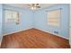 This bright bedroom includes hardwood floors, light blue walls, and two windows at 6516 Maddox Rd, Morrow, GA 30260