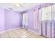 Bedroom with lilac walls, tile floor, and window with patterned curtains at 3556 Riley Rd, Douglasville, GA 30134