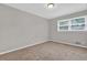 A bedroom with neutral walls, tan carpet, and a window at 6503 Tent Valley Dr, Riverdale, GA 30296
