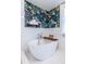 Stylish bathroom featuring a standalone soaking tub, tropical wallpaper, and white subway tiles at 570 Park Se Ave, Atlanta, GA 30312