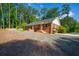 Inviting brick home with a well-maintained yard and gravel driveway, nestled among tall trees at 1382 Varner Rd, Marietta, GA 30062