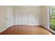 Bright bedroom features hardwood floors, closet with bi-fold doors, and natural light through a large window at 59 Oakmont Nw Dr, Marietta, GA 30064