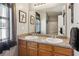 Double sink bathroom featuring framed mirrors, granite countertops, a window, and wood cabinets at 1714 Indian Way, Cumming, GA 30040