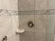 Close-up of a shower featuring gray stone-look tiles with a decorative mosaic tile accent stripe at 1150 Terramont Dr, Roswell, GA 30076