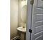 Cozy powder room with a pedestal sink, round mirror, and a stylish paneled door at 145 Scarlett Place Dr, Bowdon, GA 30108