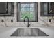 Close-up of a modern kitchen sink with stone countertop and backsplash, and sleek black faucet at 63 Lakeview Ln, Stockbridge, GA 30281