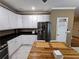 Kitchen with stainless steel refrigerator, white cabinets, stone countertops, and wooden breakfast table at 1988 Greensferry Gln, Lawrenceville, GA 30043