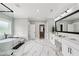 Bright bathroom featuring marble floors, soaking tub, walk-in shower, and double vanity at 2243 Cain Cir, Dacula, GA 30019