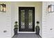 Elegant front door with glass panels, flanked by stylish sconces and manicured topiaries at 2243 Cain Cir, Dacula, GA 30019