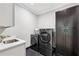 Modern laundry room with a front-load washer and dryer set and dark cabinets at 2243 Cain Cir, Dacula, GA 30019