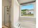 Bright bathroom features a soaking tub with a large window offering neighborhood views and a glass-door shower at 119 Hardy Water Dr, Lawrenceville, GA 30045