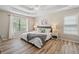 A light-filled main bedroom with tray ceilings features wood floors, a queen bed and two windows with white blinds at 2081 Township Dr, Woodstock, GA 30189