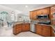 Well-lit kitchen with stainless steel appliances, granite counters, wood cabinets, and seamless access to the dining area at 410 Beechwood Ln, Woodstock, GA 30189