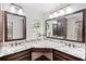Spacious bathroom featuring dual vanity with granite countertop, dark cabinets, framed mirrors, and mosaic backsplash at 2502 Tritt Springs Ne Trce, Marietta, GA 30062