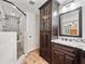 Bathroom featuring dual sink vanity, dark cabinets, granite countertops, and glass-enclosed shower at 2502 Tritt Springs Ne Trce, Marietta, GA 30062