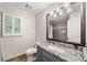 Well-lit bathroom featuring a granite countertop, window with shutters, and a framed mirror at 2502 Tritt Springs Ne Trce, Marietta, GA 30062