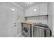 Well-lit laundry room with modern washer and dryer units, white cabinets, and a wood countertop at 5105 Ashley Falls Ct, Loganville, GA 30052