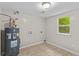 A well-lit laundry room with a tanked water heater and tile floors at 1179 Chatham Rd, Buford, GA 30518