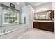 Luxurious main bathroom with soaking tub, large window, and white tile floor at 2505 Ridgehurst Dr, Buford, GA 30518