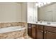 Bathroom with soaking tub, double vanity, tiled floors, dark wood cabinets and a large mirror at 680 Emeril Dr, Avondale Estates, GA 30002