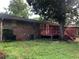 A brick house with a red painted deck and lots of green yard and trees at 4485 Merlin Ne Cir, Douglasville, GA 30134
