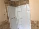 Bathroom shower with tan tiling and installed shelving unit at 4485 Merlin Ne Cir, Douglasville, GA 30134