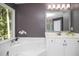 Bright bathroom featuring a tub, white vanity, and mosaic-trimmed mirror at 6435 Ivey Creek Cir, Cumming, GA 30040