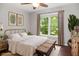 Staged bedroom showcases a comfortable bed, bench, and natural light from the window at 6435 Ivey Creek Cir, Cumming, GA 30040