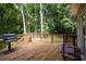 Wooden deck with an outdoor grill, surrounded by lush greenery and trees at 6435 Ivey Creek Cir, Cumming, GA 30040