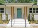 Close up of front entrance boasting natural wood pillars, teal door, and contemporary black metal railings at 401 Cottonwood Dr, Woodstock, GA 30189