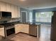 Spacious kitchen with granite countertops, stainless steel appliances, sleek white cabinetry, and wood flooring at 4635 Tims Pl, Snellville, GA 30039