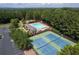 Aerial view of a community pool, tennis courts, parking, and a clubhouse, surrounded by lush greenery at 1001 Braelin Ct, Woodstock, GA 30189