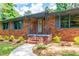 Inviting brick home featuring a cozy front porch with gray trim and lush landscaping at 3219 W Manor Ln, Atlanta, GA 30311
