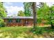 Charming brick home with well-maintained lawn, gray shutters and mature trees providing shade at 3219 W Manor Ln, Atlanta, GA 30311